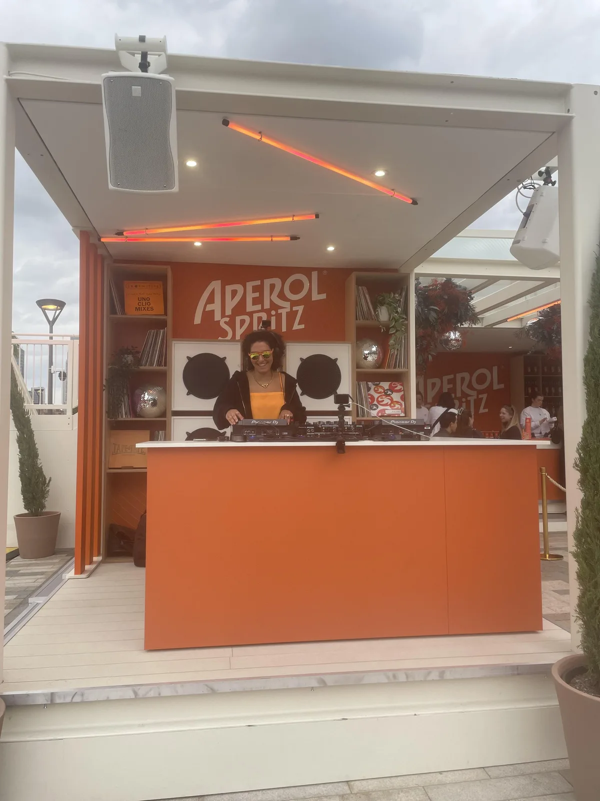 A DJ playing vinyl behind the Aperol Spritz branded booth at the Aperidisco residency