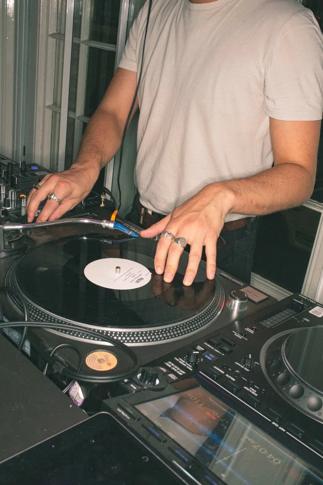 A DJ's hands cueing a record on a turntable during an in-store set